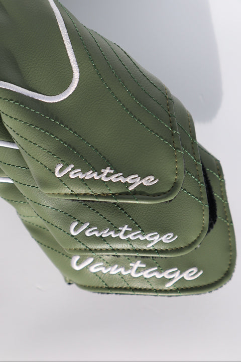 Close-up of sage green golf club headcover sleeves with white piping and the brand name 'Vantage' embroidered in white script.
